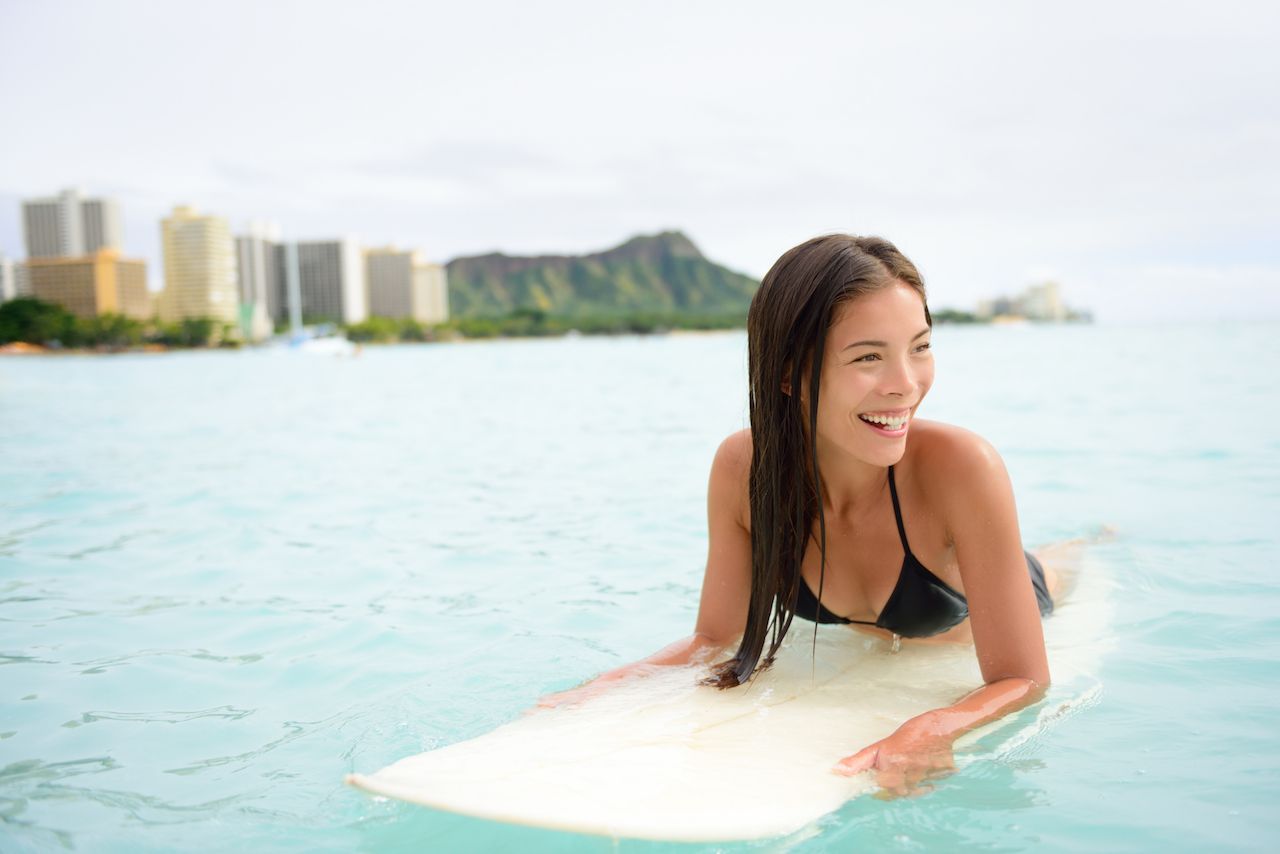 Woman lying on surfboard in Waikiki