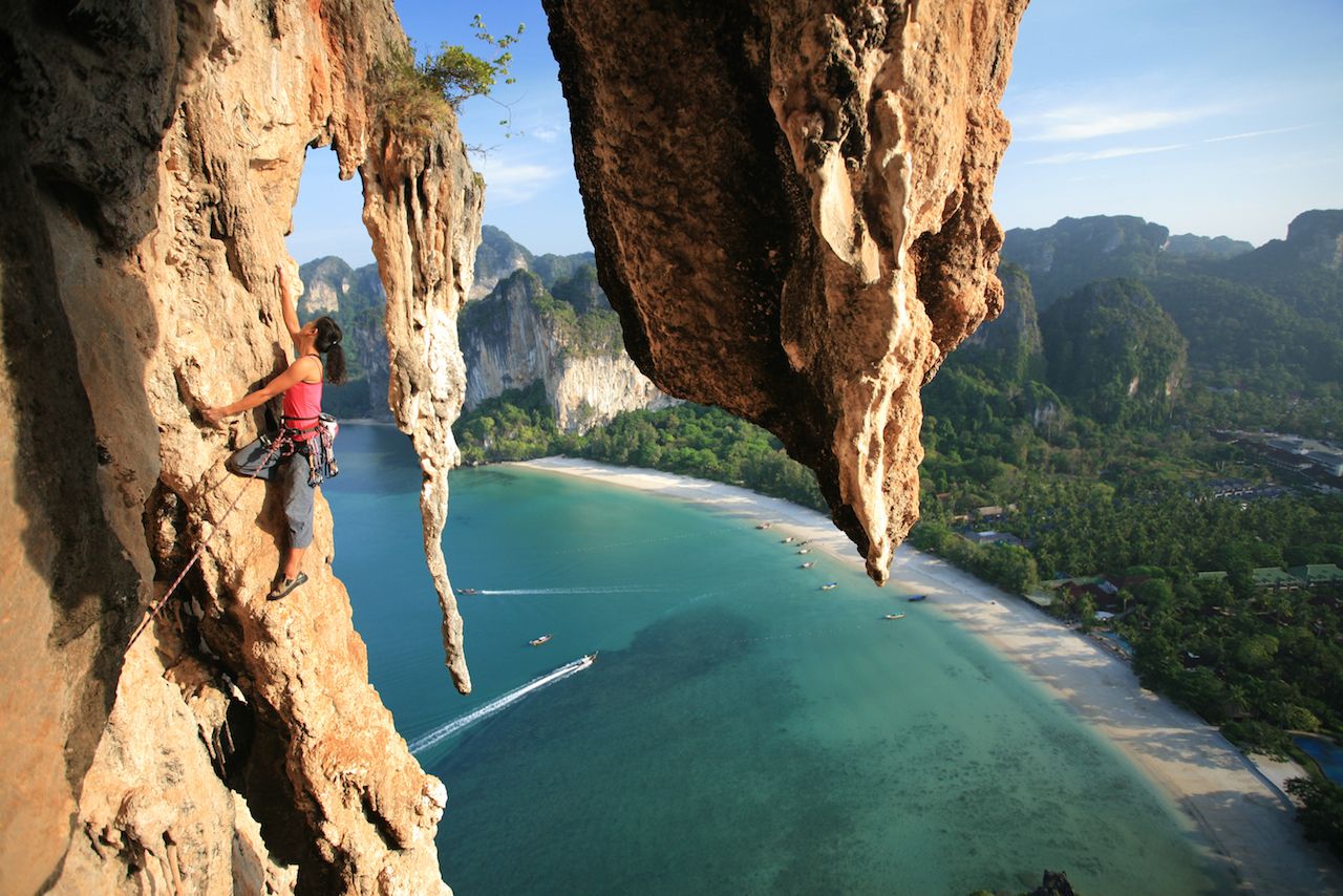 Stunning beautiful female professional climber rock climbing mountain multi pitch in Thailand cliff